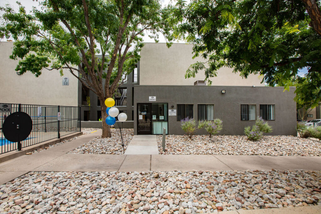 Leasing office exterior with sidewalks lined with rocks and large trees