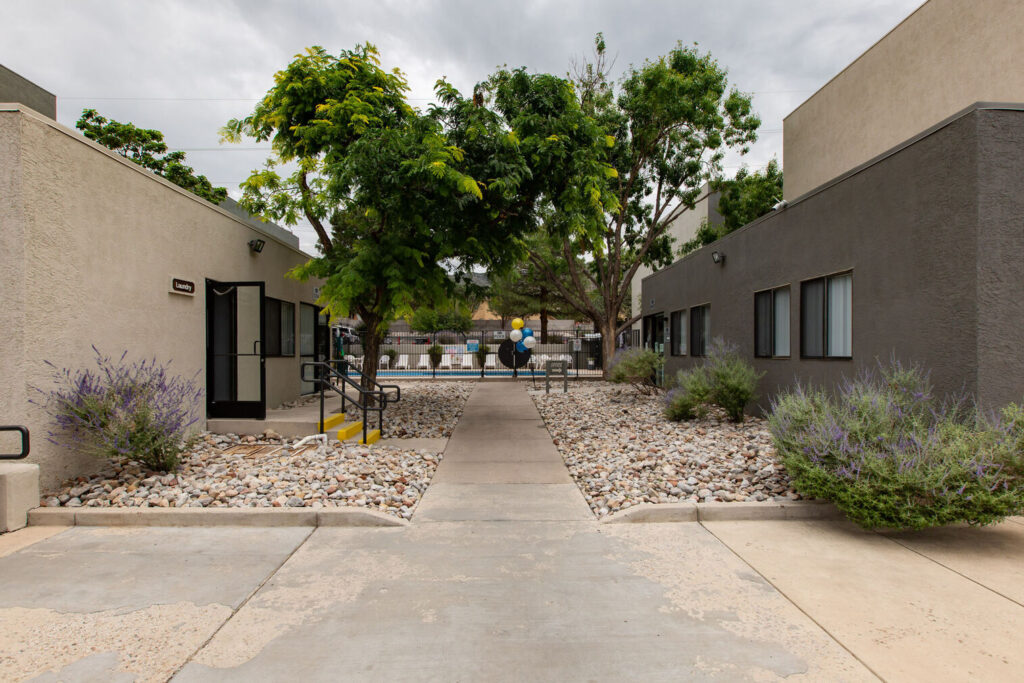Leasing office exterior with sidewalks lined with rocks and large trees