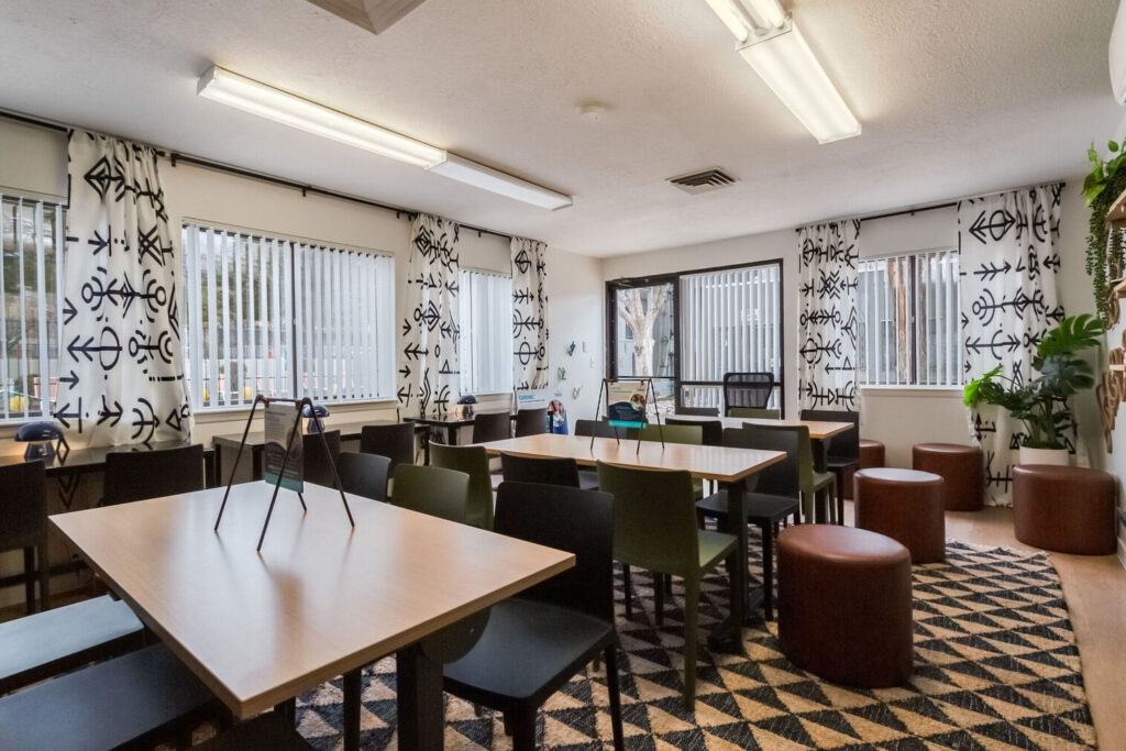 Kids club with desks and chairs, large windows, and shelves with books and games