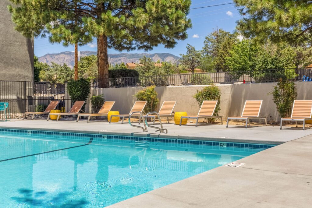 Pool with deck chairs and large shady trees